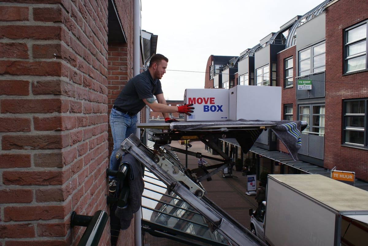 Verhuizer van Flo-Rent laadt een doos op de verhuislift