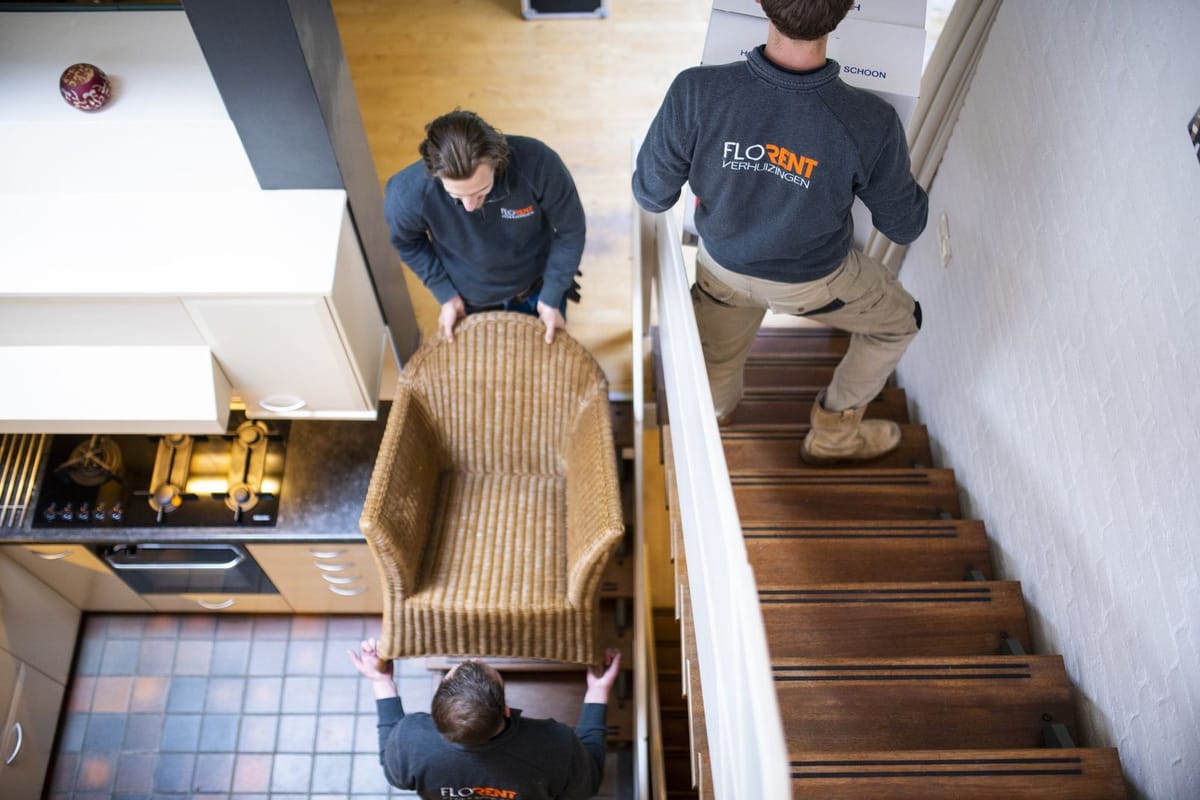 Flo-Rent verhuizers dragen een fauteuil de trap af